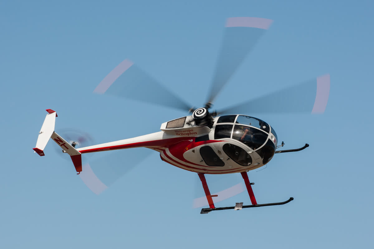 Red and white helicopter in flight against a blue sky
